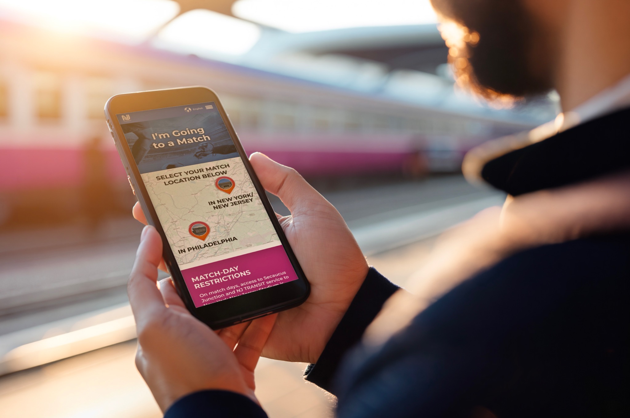 Traveler using the NJ TRANSIT World Cup mobile website at a train platform